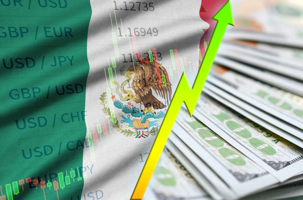 Mano señalando caída en indicadores económicos frente a la bandera de México, ilustrando retos fiscales para inversionistas extranjeros.