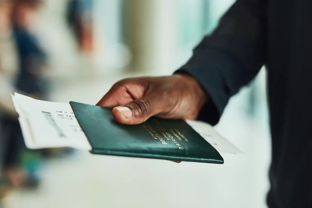 Mano entregando pasaporte y boleto en mostrador de aeropuerto.