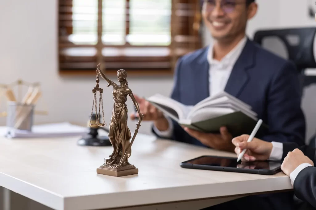 Estatua de la justicia sobre escritorio con abogado leyendo leyes de inmigración