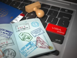 Pasaporte con sellos sobre teclado y botón de solicitud de visa en línea