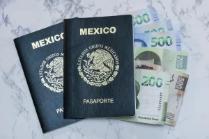 Pasaportes mexicanos colocados sobre billetes de 500 pesos, representando los costos de trámites migratorios