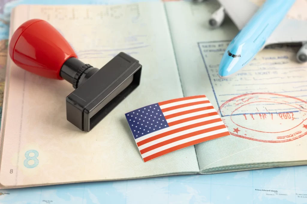 Mesa con sello migratorio, pasaporte y bandera de EE.UU., representando el proceso de verificación de lazos fuertes para visa de turista.