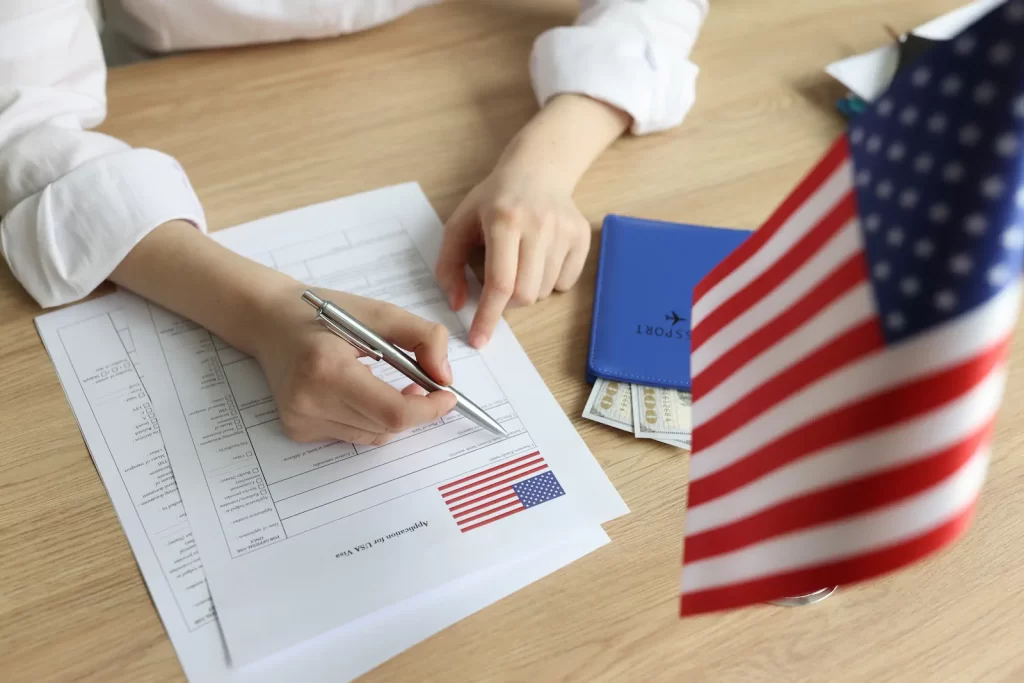 Persona firmando documentos oficiales como comprobantes laborales o financieros para demostrar lazos fuertes en una solicitud de visa.