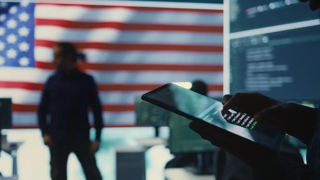 Persona utilizando tablet frente a bandera de Estados Unidos para gestionar empresa como extranjero