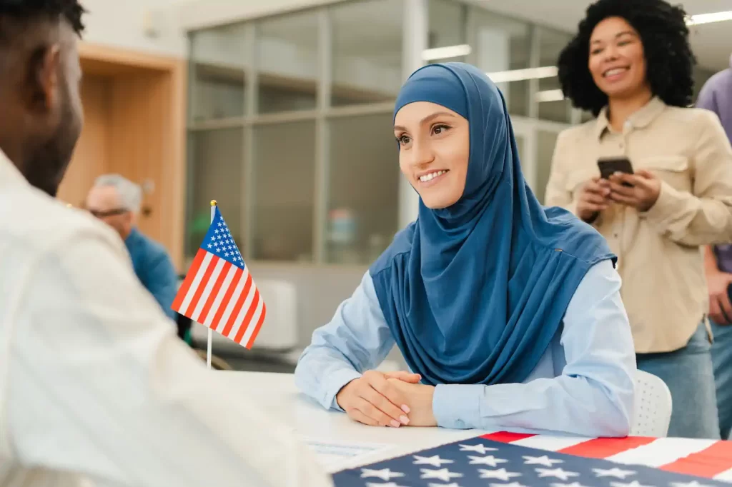 Mujer en entrevista de visa estadounidense con bandera de Estados Unidos en escritorio