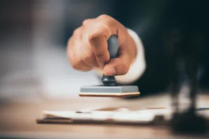 Mano estampando sello oficial sobre documentos para apostilla