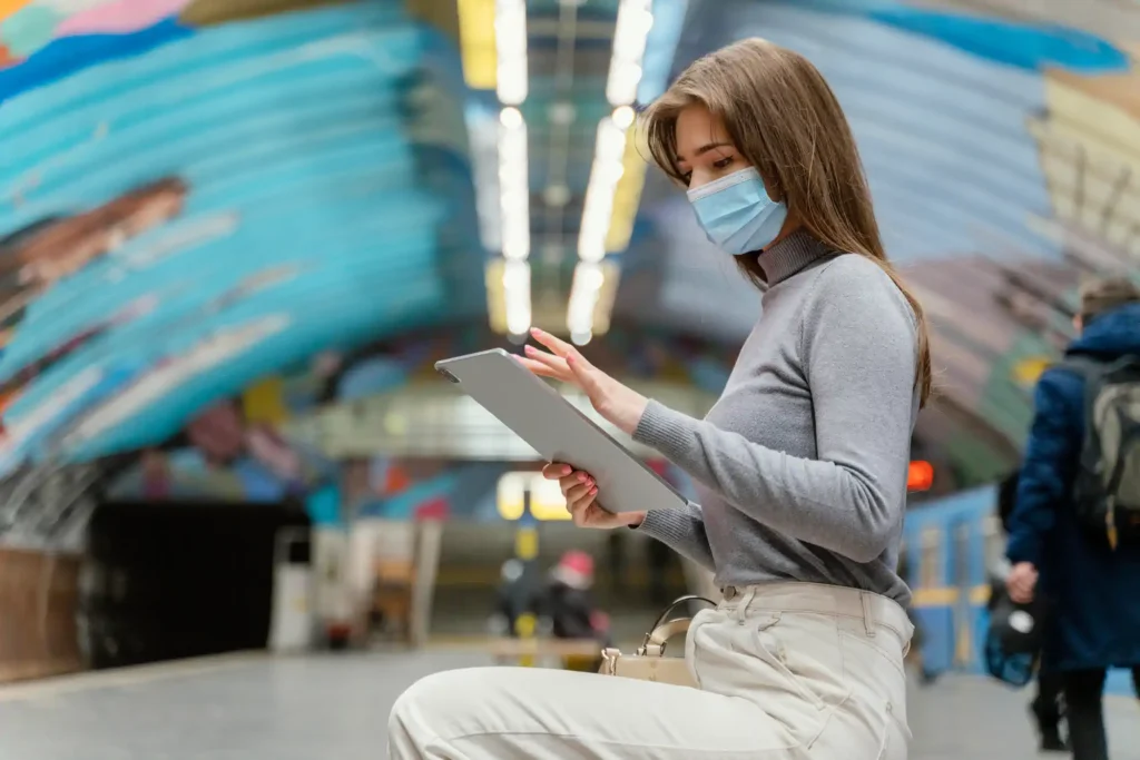 Mujer con mascarilla usando tablet en estación moderna