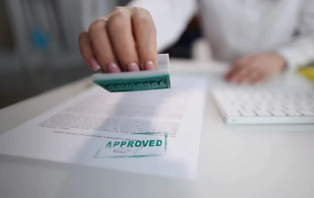 Mano sellando documento con sello de aprobado
