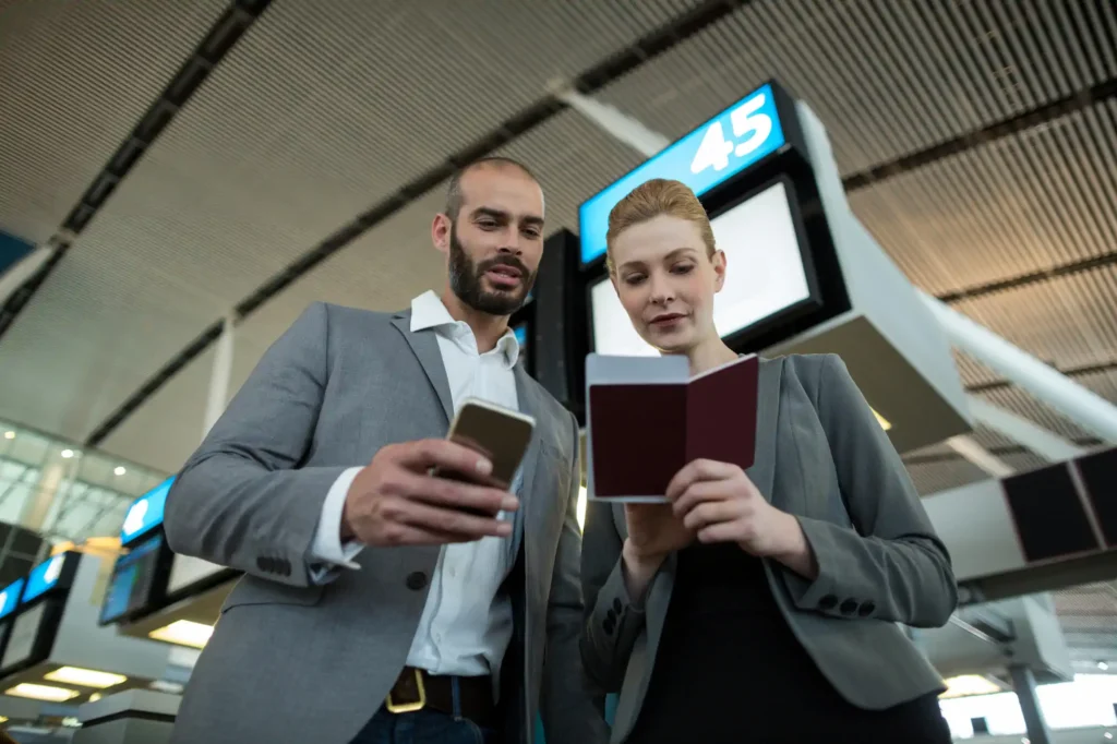 Viajeros de negocios consultando móvil en aeropuerto