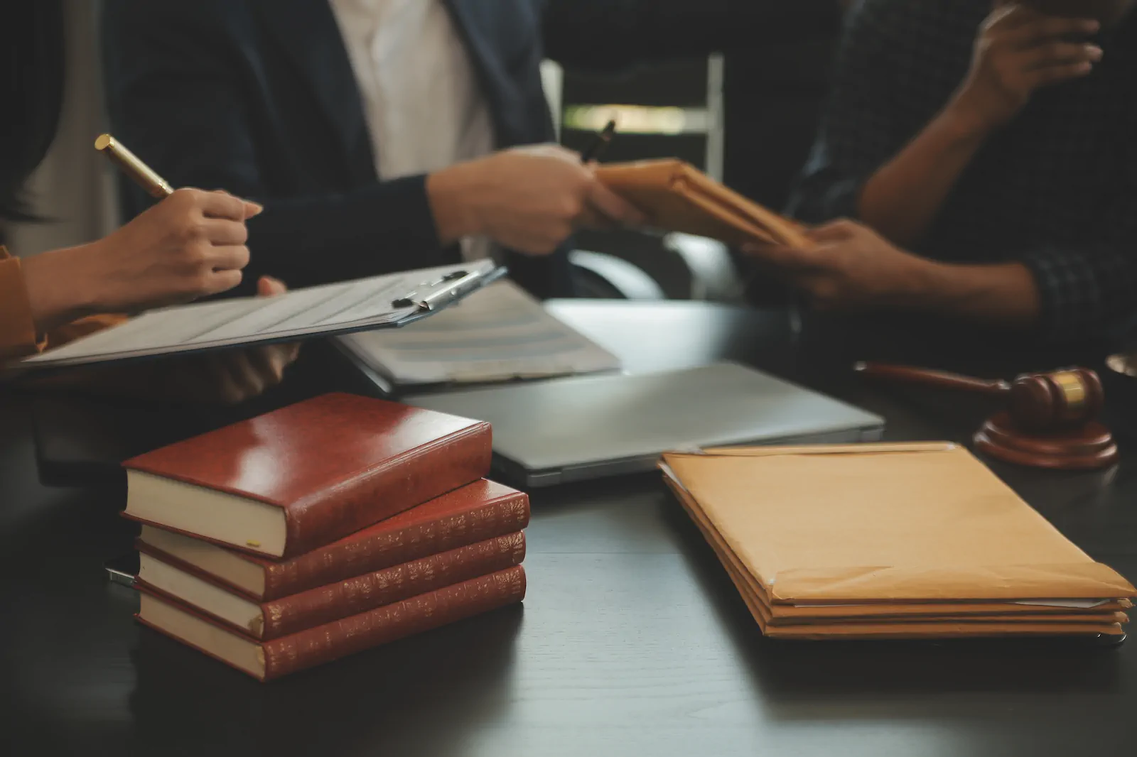 Abogados revisan documentos junto a libros jurídicos y un mazo